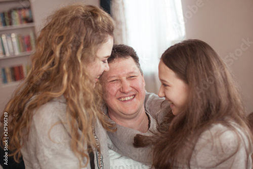 portrait of a happy father and beautiful daughters, they laugh, indoor