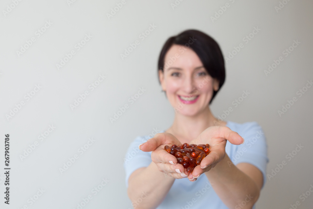 Female portrait vertical shot hand holding orange pills