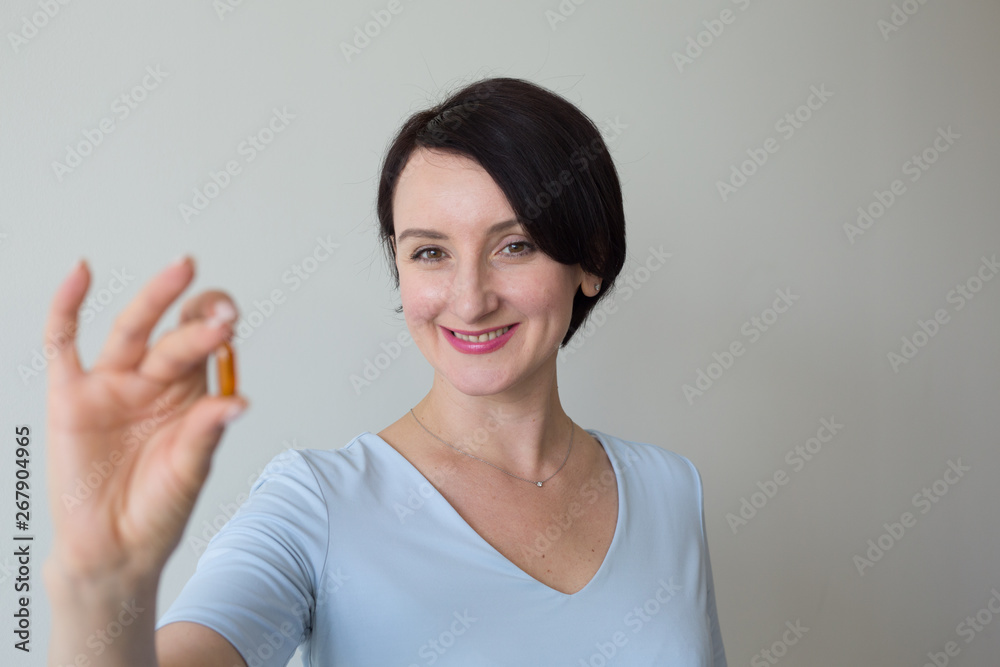 Female portrait vertical shot hand holding orange pills Female portrait vertical shot hand holding orange pills