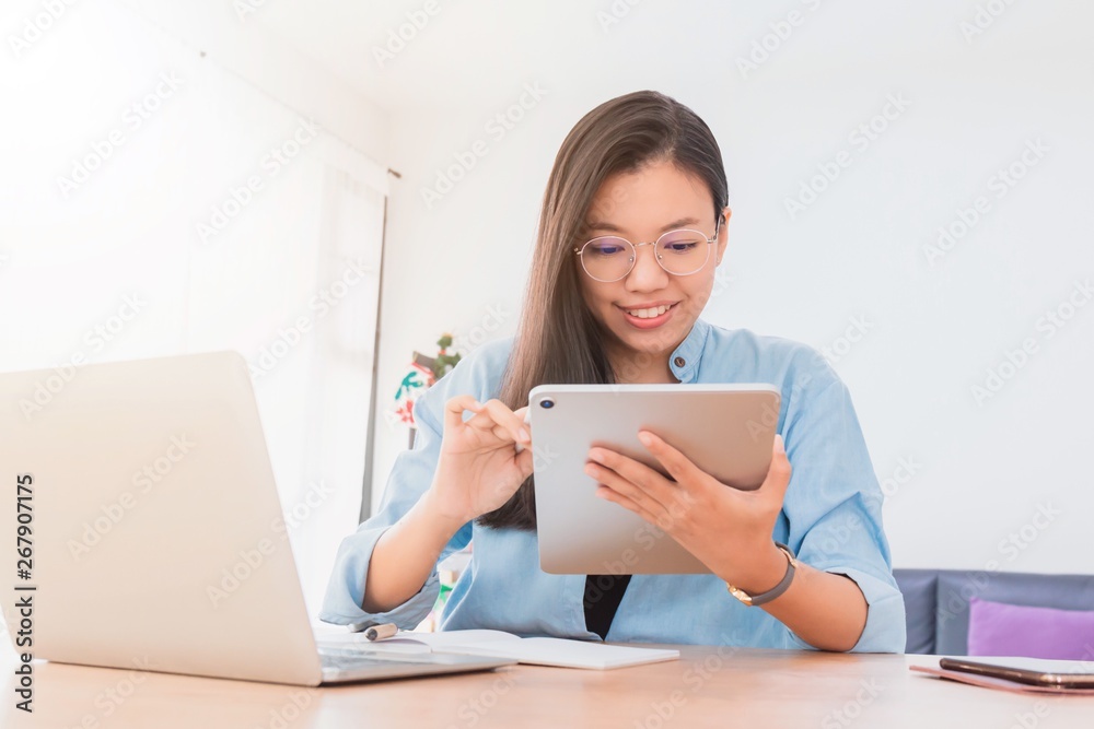 Young beautiful Asian woman working with laptop,smartphone and tablet in home office background.Concept of female freelancer using gadget mobile technology.