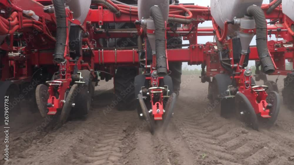 close-up, tractor with special precision planters, seeder is working in the field, agricultural machinery is planting corn, or sunflower seed into freshly plowed land.