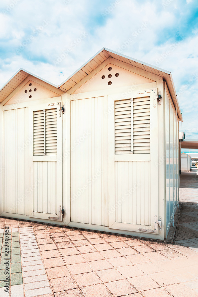 Two beach cabins, blue sky and clouds on background