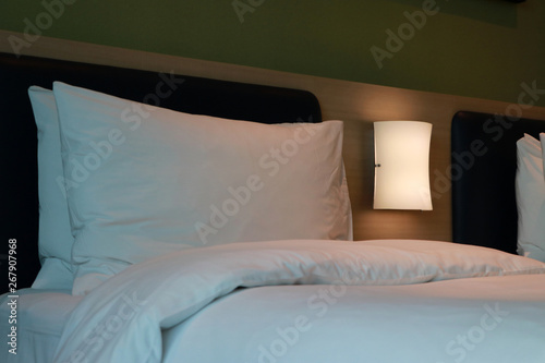 White pillow with white mattress and light dim on the bed.