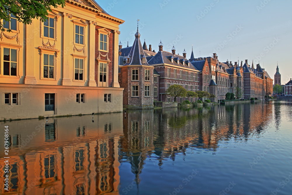 Reflections of the Mauritshuis and the Binnenhof on the Hofvijver lake at sunset, with the clock tower of Grote of Sint Jacobskerk on the right, The Hague, Netherlands