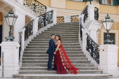 Canvas Print Beautiful woman in a long red dress walks around the city with her husband in a