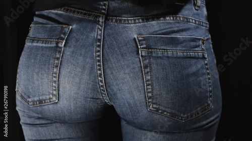 Girl pulls out of the back pocket of jeans. Close-up. Woman hiding gun behind his back isolated on black background.