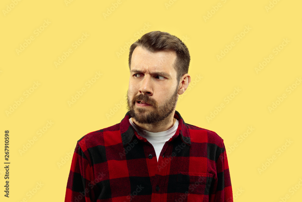 Half-length close up portrait of young man in shirt on yellow background. The human emotions, facial expression concept. Front view. Trendy colors. Negative space. Serious and thoughtful looking. Half-length close up portrait of young man in shirt on yellow background. The human emotions, facial expression concept. Front view. Trendy colors. Negative space. Serious and thoughtful looking.