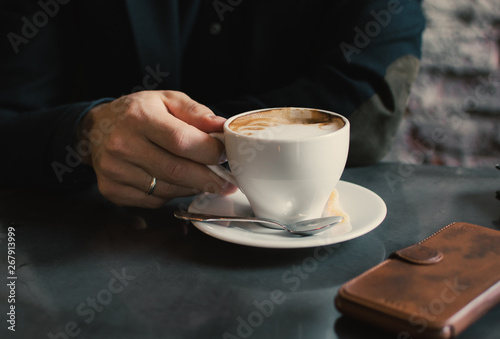 Man holding a cup of cappuccino.