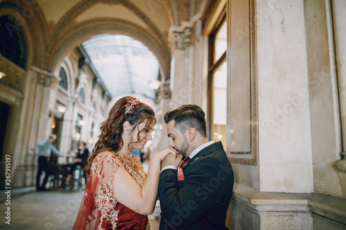 Canvas Print Beautiful woman in a long red dress walks around the city with her husband in a