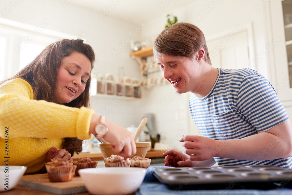 Young Downs Syndrome Couple Decorating Homemade Cupcakes With Icing In Kitchen At Home Young Downs Syndrome Couple Decorating Homemade Cupcakes With Icing In Kitchen At Home