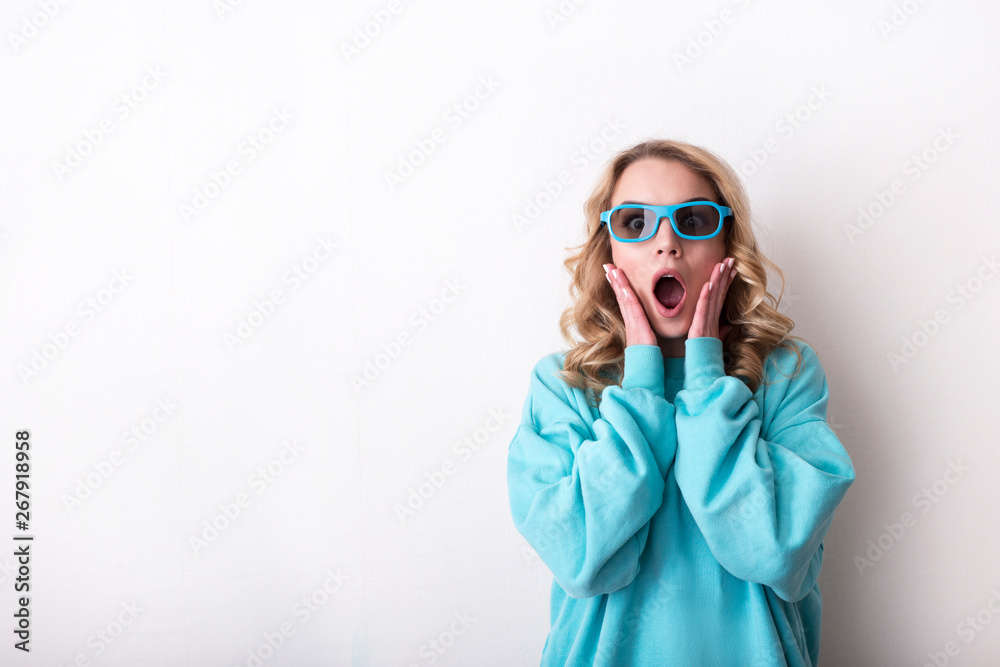 Beautiful young emotional woman in 3d glasses on a light background. Cinema concept