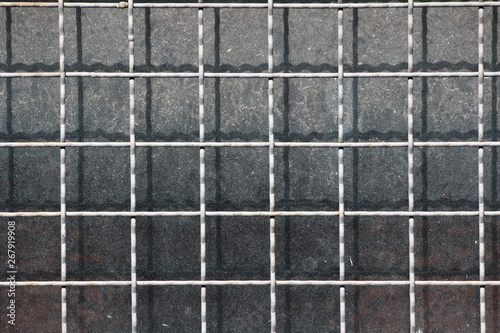 Background wallpaper texture of net shaped metal bars protection mounted on old dirty windows of abandoned industrial complex building on warm sunny spring day