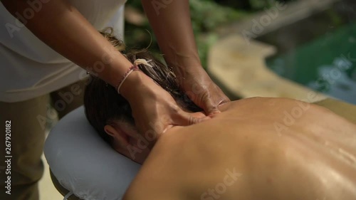 close-up Thai masseuse makes neck massage in spa outside area for young client