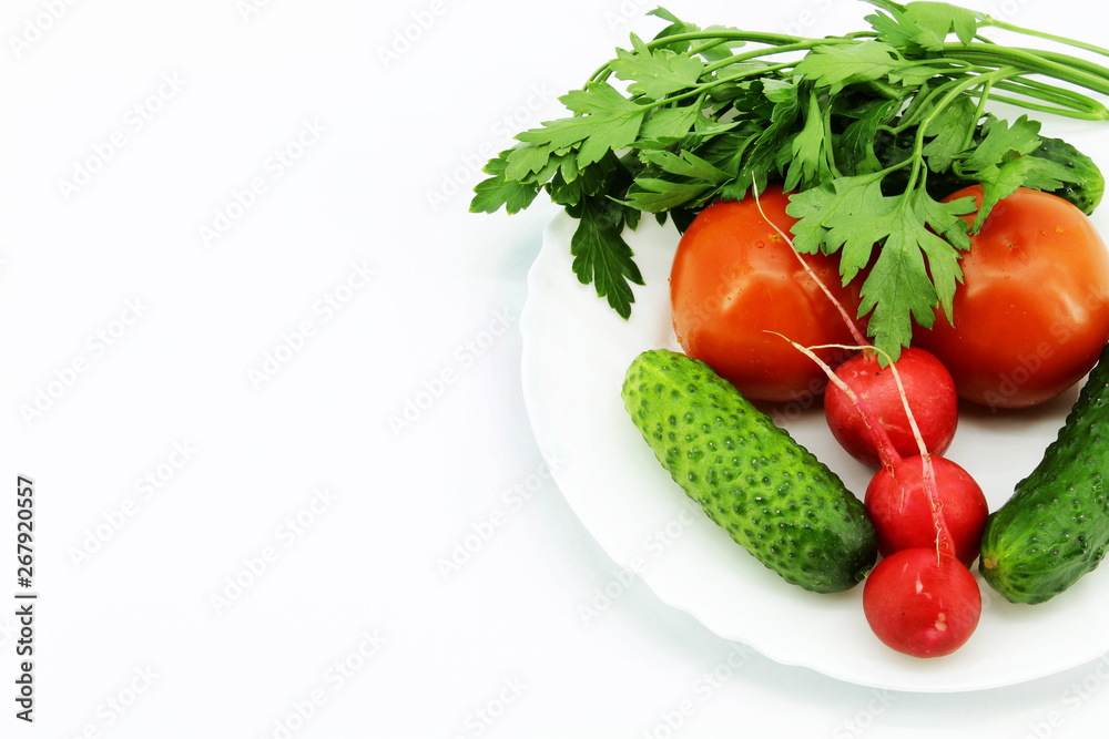 Vegetables and greens in a plate on a white background