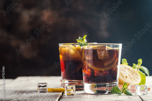 Fresh made Cuba Libre with brown rum, cola, mint and lemon on wooden background