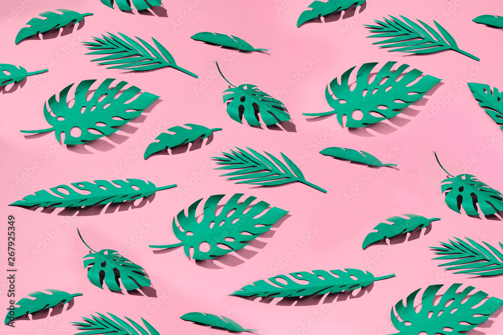 tropical leaves cut from paper on a pink background.