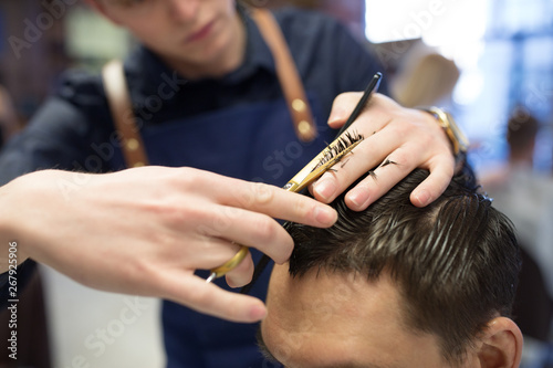grooming, hairdressing and people concept - close up of male client and hairdresser with comb and scissors cutting hair at barbershop