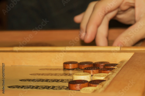 backgammon game. at the background, the blurred player's hand moves the chip