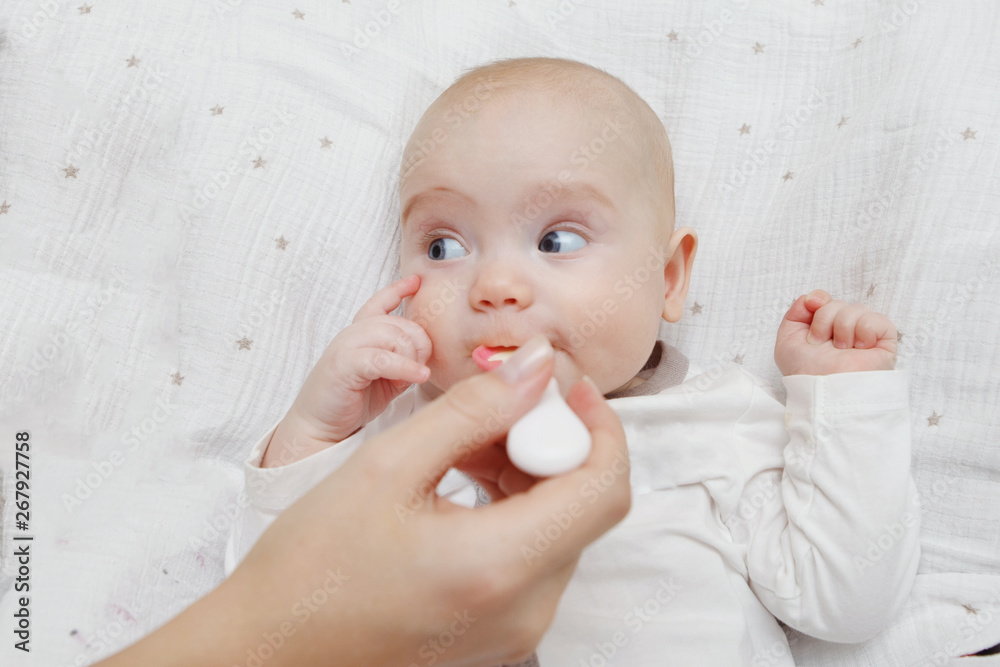 Beautiful Lovely five-month baby girl eating with a spoon. Healthy food. Maternal care. Childcare. Close-up. Beautiful Lovely five-month baby girl eating with a spoon. Healthy food. Maternal care. Childcare. Close-up.