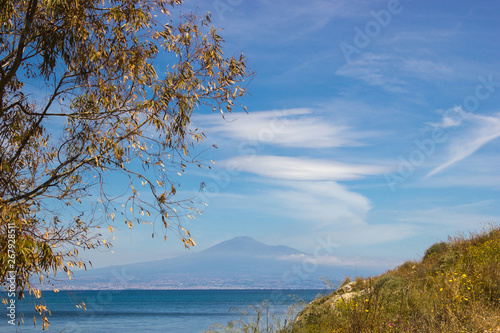 Brucoli view of seascape in a frame with a tree and grass aside and the blue sea and sky with Etna in background © AlessioDCAuditore
