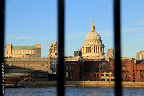 Thames river view with riverside buildings and st pauls cathedral dome look through blurred rail.