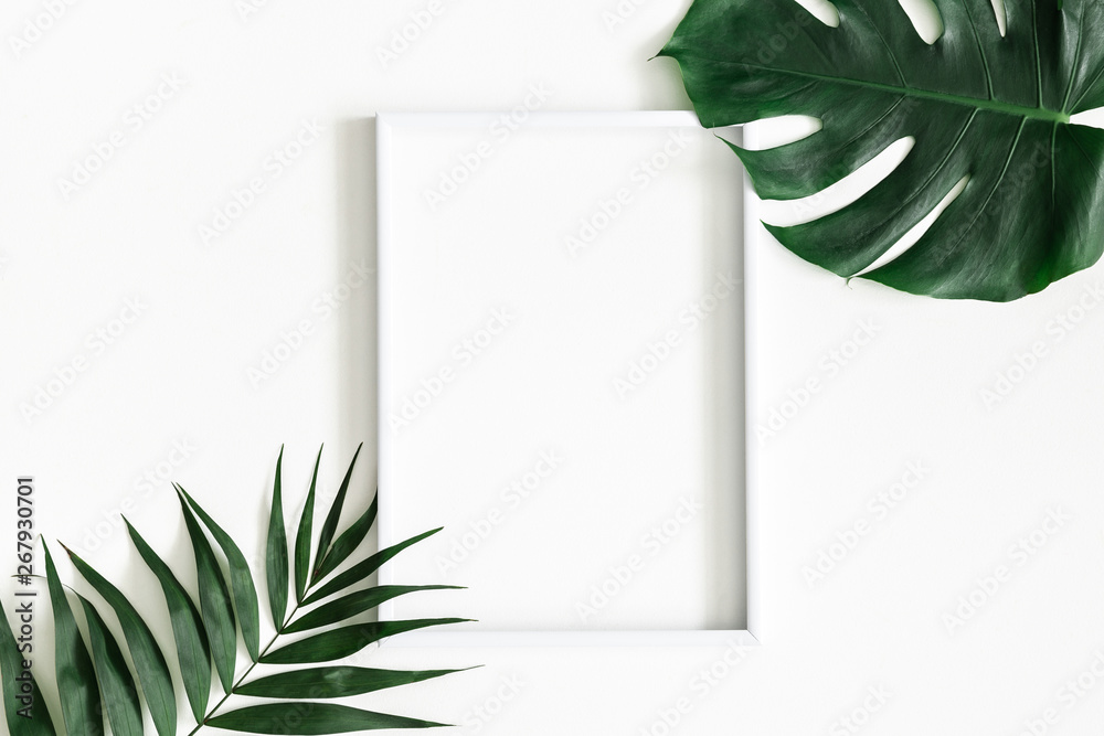 Summer composition. Tropical palm leaves, white photo frame on white background. Summer, nature concept. Flat lay, top view, copy space - obrazy, fototapety, plakaty 