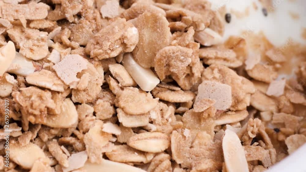 Sprinkling whole grains and almond sliced in yogurt bowl, slow motion. Sprinkling whole grains and almond sliced in yogurt bowl, slow motion.
