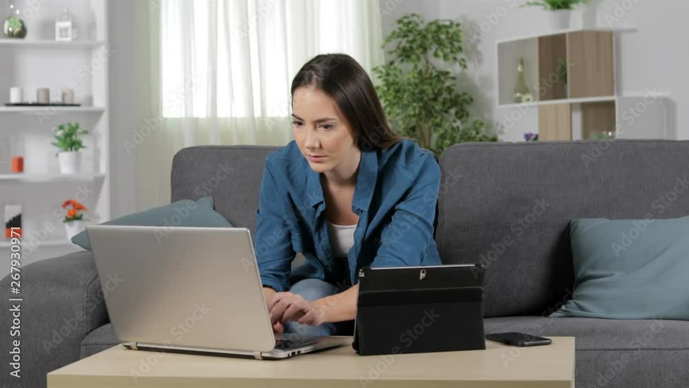 Serious woman talking on phone using multiple devices at home