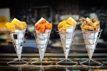 Sea food in cones at counter in small street shop in Spain – snack with mixed takeaway grilled fish and fried seafood – to go delicious roasted octopus, anchovies and calamari ready to eat by tourists