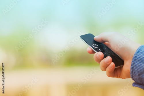 Hand holding remote control. Blured background. Remote control devices concept. Space for a text. Close up.