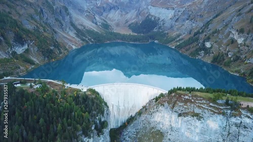 Water dam and reservoir lake aerial drone footage in Swiss Alps mountains generating hydro electricity power renewable energy and sustainable development. 4K 60fps video