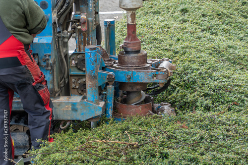Fotografie Hollow borehole auger of a dry drilling rig drills a hole in the sandy soil and produces sand on the sides