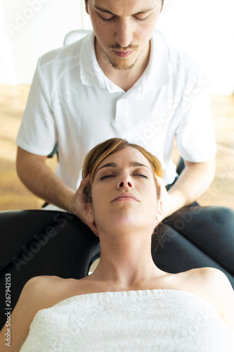 Young physiotherapist doing a neck treatment to the patient in a physiotherapy room.