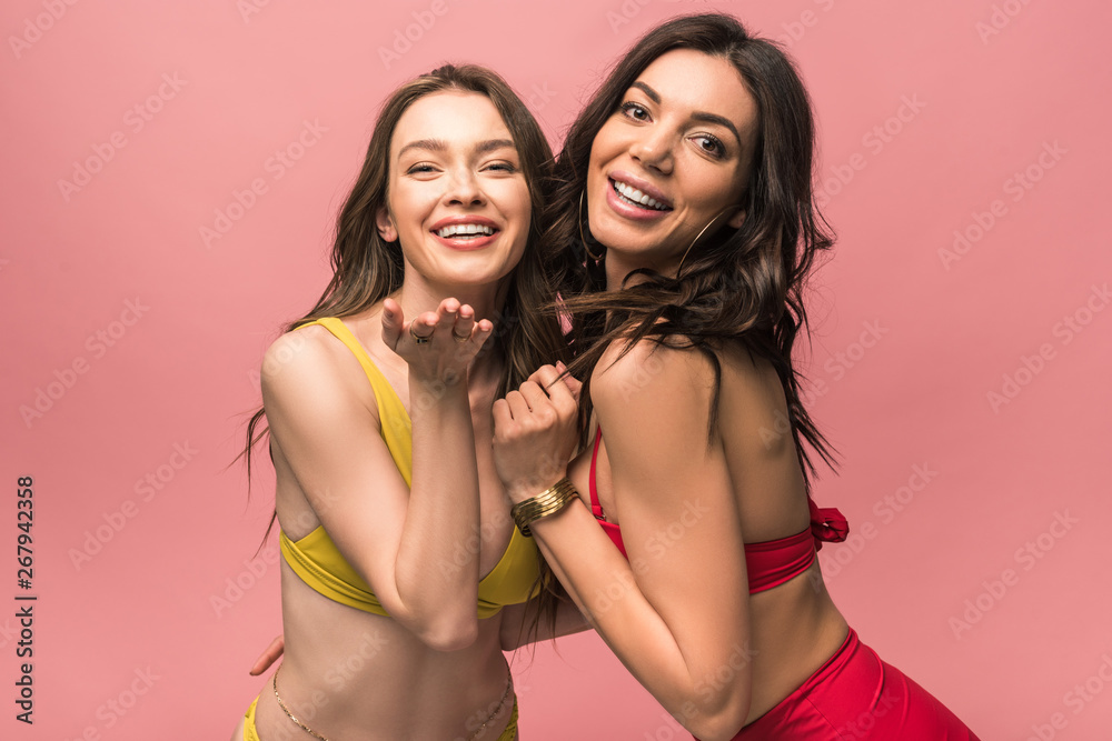 two pretty smiling girls in bikini sending air kiss isolated on pink two pretty smiling girls in bikini sending air kiss isolated on pink
