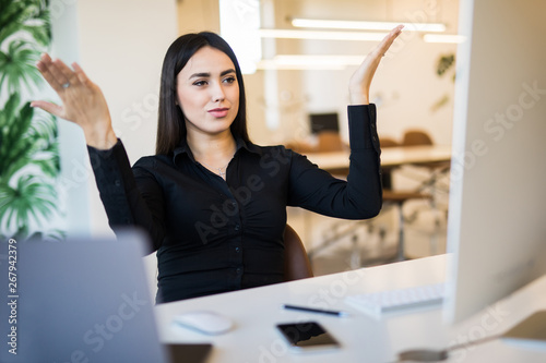 Too much work. Young pretty woman with raised hands in front of screen pc sitting in office