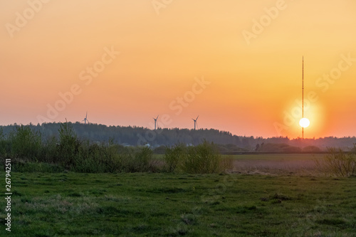 Beautiful orange sunset on the background of the forest, wind turbines. Beautiful nature outside the city
