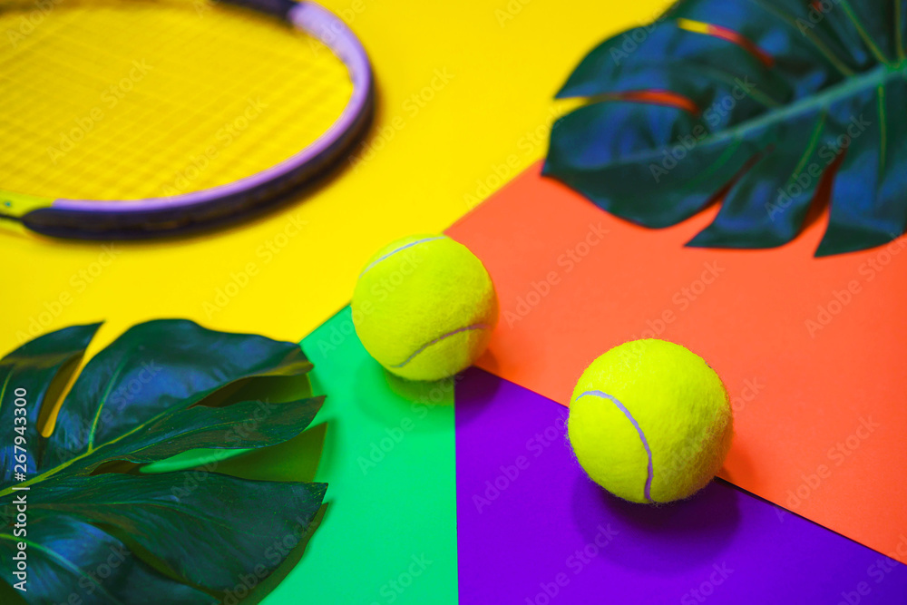 Tennis layout with tennis balls, racket and tropical monstera leaves on abstract different multicolored neon background. Sport concept with tennis play. Flat lay, top view, selective focus.