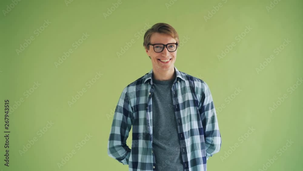 Portrait of handsome young man looking at camera and winking standing alone on green background and smiling. Flirtation, human feelings and emotions concept. Portrait of handsome young man looking at camera and winking standing alone on green background and smiling. Flirtation, human feelings and emotions concept.