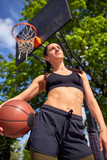 Beautiful sexy fitness girl in black sport wear with perfect body with basket ball at basketball court. Sport, fitness, lifestyle concept