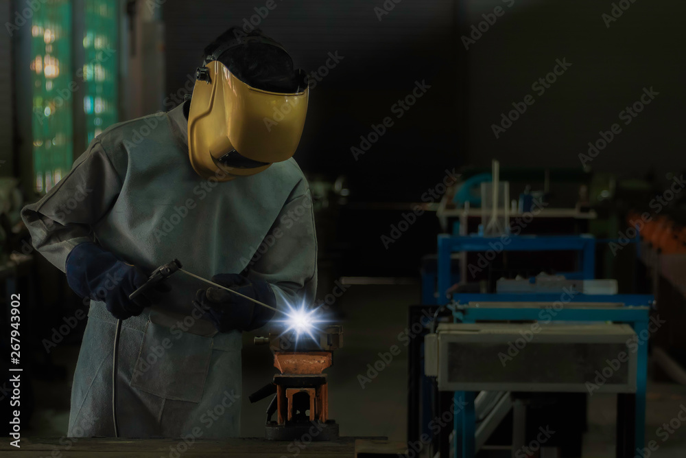 A craftman is welding with workpiece steel.Working person About welder steel Using electric welding machine There are lines of light coming out and safety equipment in factory industry.. A craftman is welding with workpiece steel.Working person About welder steel Using electric welding machine There are lines of light coming out and safety equipment in factory industry..