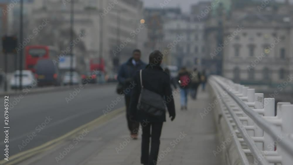 A shallow depth of field wide shot of people walking along the side of a bridge next to the road in London A shallow depth of field wide shot of people walking along the side of a bridge next to the road in London