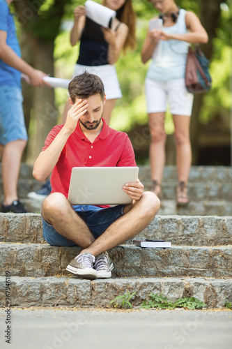 Young student using laptop outdoors