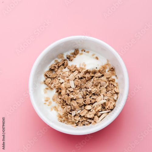 Whole grains on yogurt in white bowl, pink background.