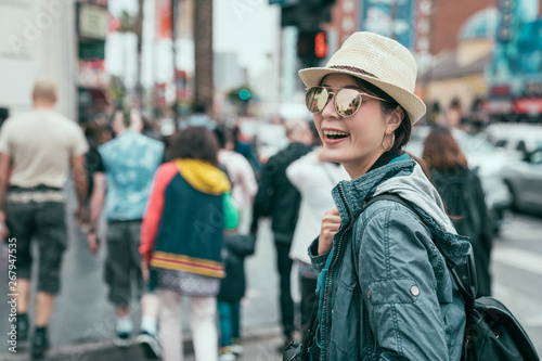 Emotional portrait of happy and cheerful beautiful teenager asian girl tourist walking through pedestrian crossing street in busy city. summertime lifestyle in america. traveler hollywood boulevard