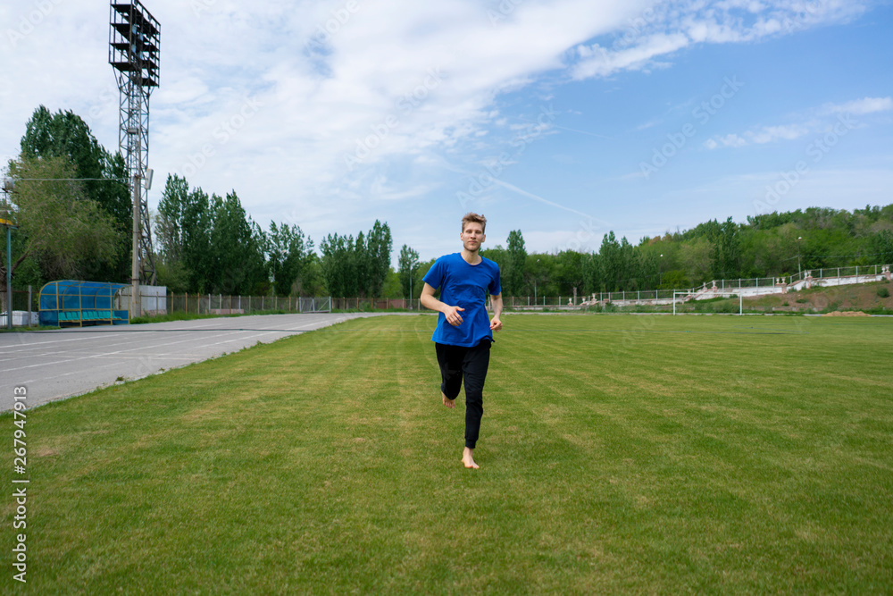 healthy morning running, male athlete on the green grass fields with bare feet