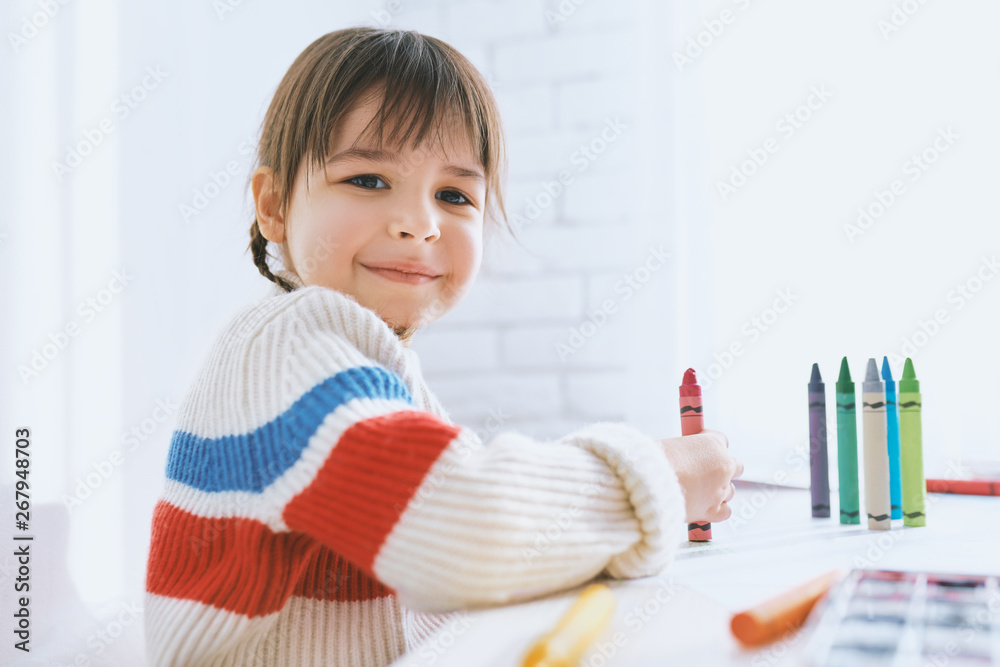 Portrait of cute little girl smiling and playing with colorful pencils. Pretty child drawing with colorful pencils on paper at the desk, sitting at home. People, childhood, education Portrait of cute little girl smiling and playing with colorful pencils. Pretty child drawing with colorful pencils on paper at the desk, sitting at home. People, childhood, education