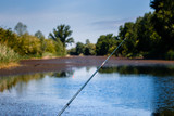 Fishing rod with blurred lake and forest in the background