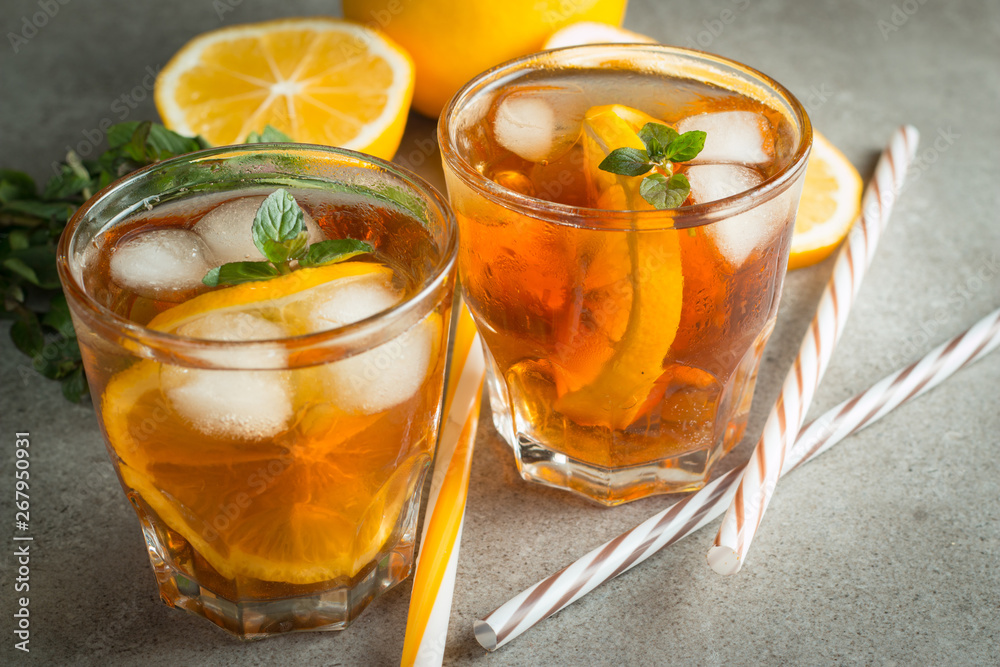 Glasses of cold ice tea with lemon, ice, mint on background. Homemade lemonade. Spring and summer drinks and beverages concept. Glasses of cold ice tea with lemon, ice, mint on background. Homemade lemonade. Spring and summer drinks and beverages concept.