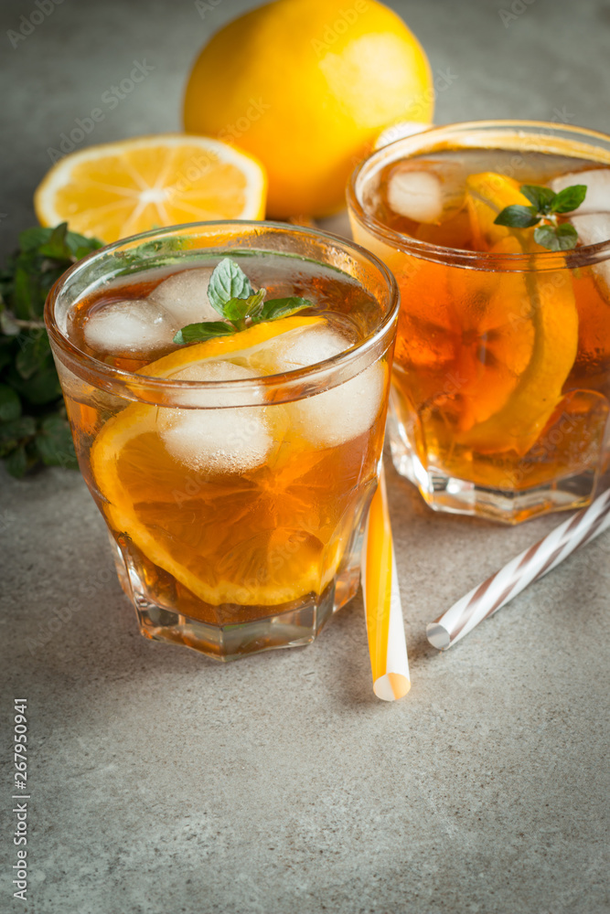 Glasses of cold ice tea with lemon, ice, mint on background. Homemade lemonade. Spring and summer drinks and beverages concept. Glasses of cold ice tea with lemon, ice, mint on background. Homemade lemonade. Spring and summer drinks and beverages concept.