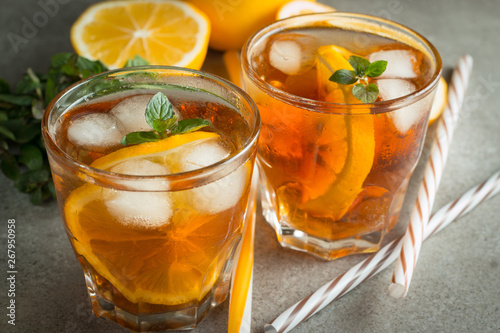 Glasses of cold ice tea with lemon, ice, mint on background. Homemade lemonade. Spring and summer drinks and beverages concept.